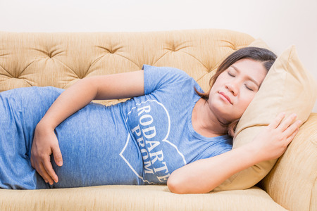Pregnant woman relaxing at home on vintage sofaの写真素材