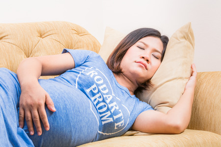 Pregnant woman relaxing at home on vintage sofaの写真素材