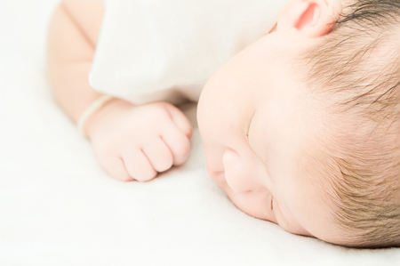 Peaceful baby lying on a bed while sleeping in a bright roomの写真素材