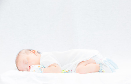 Peaceful baby lying on a bed while sleeping in a bright roomの写真素材
