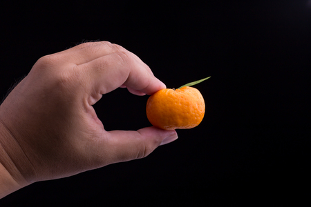 Man hand holding mandarin orange on black backgroundの写真素材