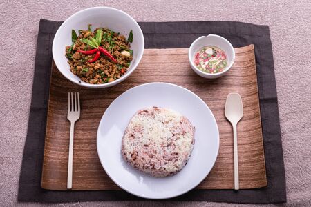 Stir fried minced pork with basil served with steamed jasmin rice and Riceberry, Thai famous spicy food, Thai name is Pad kra paoの写真素材