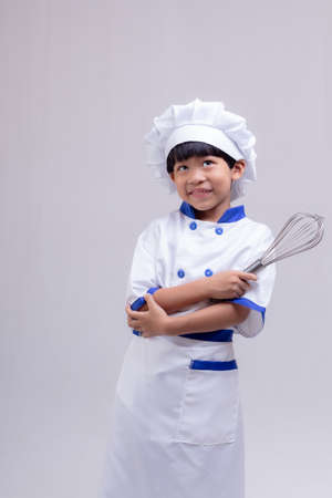 Cute boy wearing chef uniform on white backgroundの写真素材
