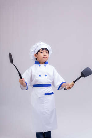 Cute boy wearing chef uniform on white backgroundの写真素材