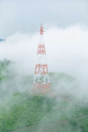 High voltage transmission towers on mountain with fog.in thailand