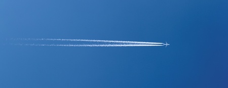 aircraft in a clear blue sky with condensation trailの写真素材
