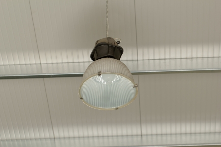 Industrial ceiling reflector with aluminium lamp vessel hanging from the roofの写真素材