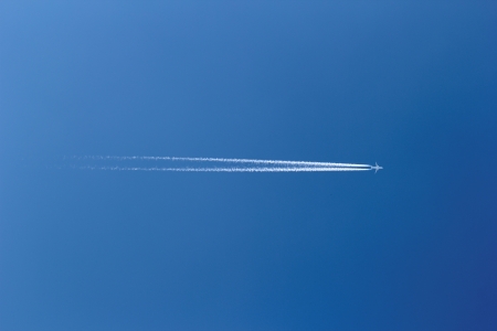 aircraft in a clear blue sky with condensation trailの写真素材