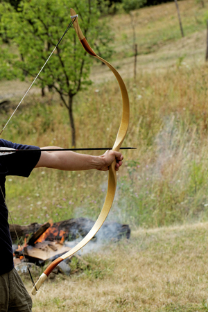 archery man shooting arrow with bow in the nature