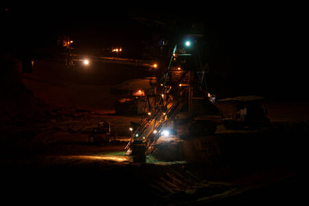 Coal mining in an open pit with huge industrial machine at night shootの写真素材
