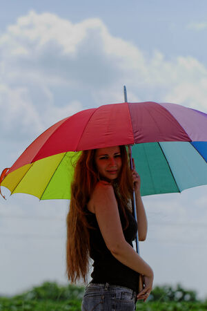 beautiful young girl with rainbow colored umbrellaの写真素材
