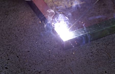 Iron welding with bright light and smoke at manufacturingの写真素材