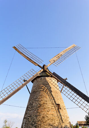 Old wooden windmill against the blue skyの写真素材