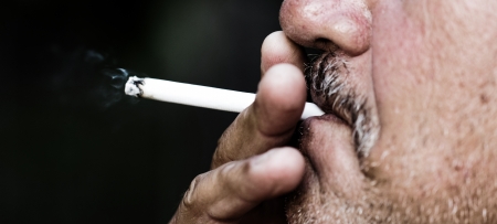 Smoking a cigarette against a dark backgroundの写真素材