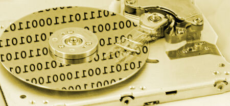 Internals of a computer harddrive with binary number reflections with yellow colors (HDD, winchester)の写真素材