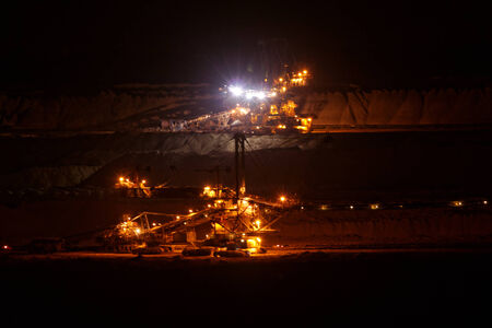 Coal mining in an open pit with huge industrial machine at night shootの写真素材