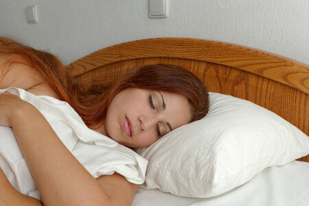 beautiful girl with long brown hair sleeping in the white bedの写真素材