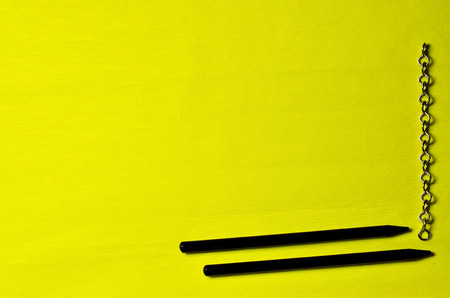 Chain and black pencils on a yellow backgroundの写真素材