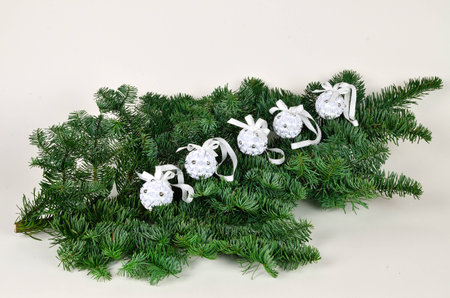 Five white paper Christmas balls on a green branchの写真素材