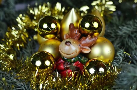The tiny reindeer between the golden Christmas  ornamentsの写真素材