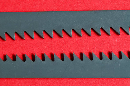 Two dark saw blades on the red background. Focus is on the center of the saw blades.の写真素材