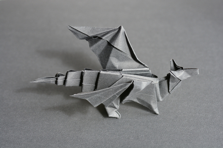 Gray origami paper dragon on gray backgroundの写真素材