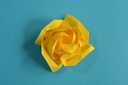 Yellow origami paper flower on blue backgroundの写真素材