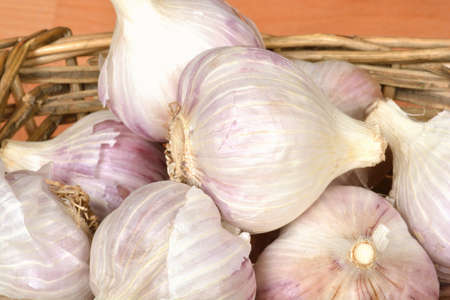 Detail if Garlic bulbs in a basket on a wooden surface