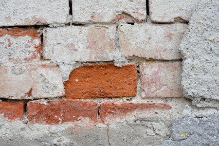 Detail of an old wall with cracked fasade and bricks underneathの写真素材