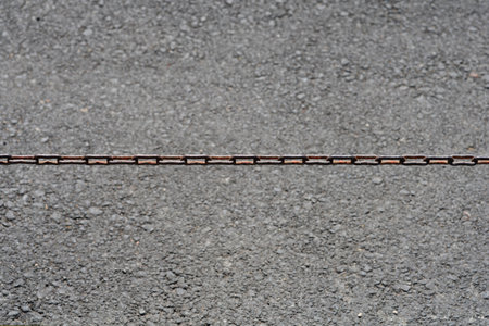 Detail of a chain over asphalt roadの写真素材