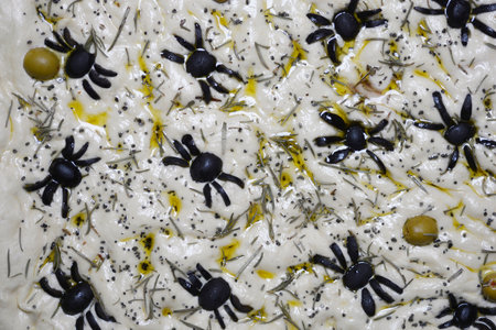 Detail of unbaked focaccia with black olives shaped like spiders for Halloweenの写真素材