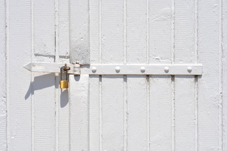 Detail of a white painted wooden fence gate with a padlockの写真素材