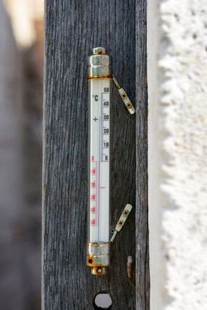 Old thermometer on a wooden plank showing a temperature of 33 degrees Celsiusの写真素材