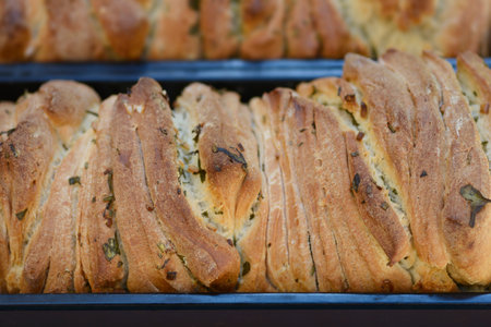 Two loaves of freshly baked pull apart bread with garlic and rosemary in metal pans