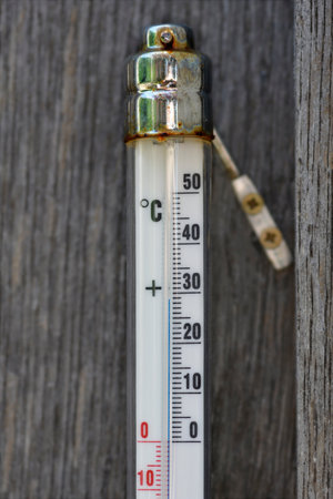 Old thermometer on a wooden plank showing a temperature of 29 degrees Celsius
