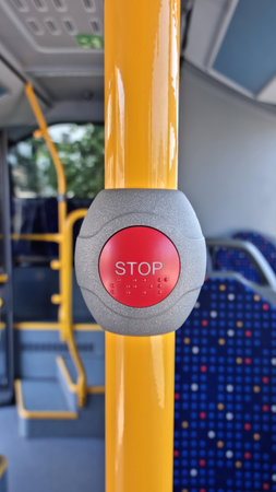An accessible red emergency stop button in a bus with Braille markings, allows visually impaired...