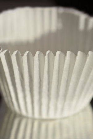 Detail of a white paper muffin liner with fluted edges with reflectionの写真素材