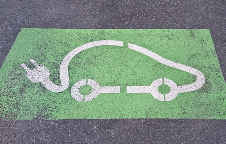 White symbol of an electric car on a green surface painted on asphalt, indicating a parking spot for EV charging stationの写真素材