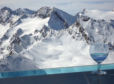 Drink in Alps. Otztal Alps viewed from the balcony of the bar on the top of Tiefenbachkogl (3309 m) in the Solden ski resort in Austria with the glass of drink standing on the external bar.の写真素材