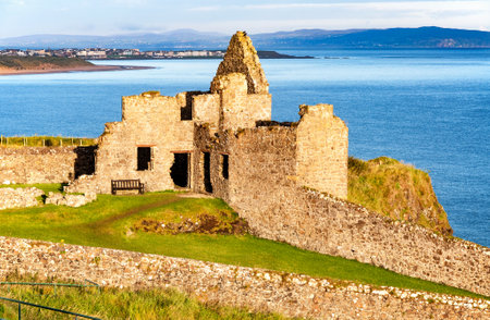 Fragment of ruins of Dunluce castle in County Antrim, Northern Ireland, UK, with the far view of  Portrush resort in the backgroundのeditorial素材