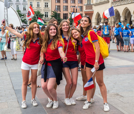 KRAKOW, POLAND - JULY 27, 2016: A group of French girls in red, female pilgrims, making selfies on the Market Square in Cracow during the World Youth Day 2016のeditorial素材