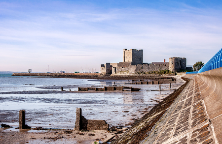 Medieval Norman Castle in Carrickfergus near Belfast, Northern Ireland, and Belfast Lough during a low tideの写真素材