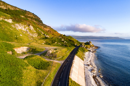 The eastern coast of Northern Ireland and Antrim Coast Road, a.k.a. Giant's Causeway Coastal Route with concrete revetments. Aerial view at sunrise.の写真素材