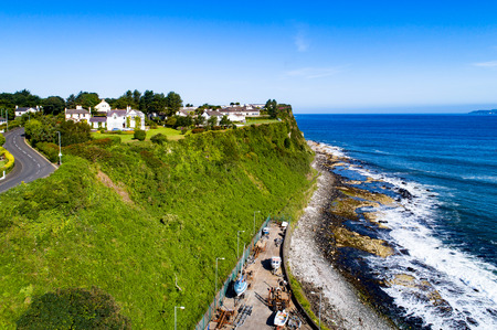 Atlantic coast with a steep cliff, marina and Causeway Coastal Road at Ballycastle, County Antrim, Northern Ireland, UK. Aerial viewの写真素材