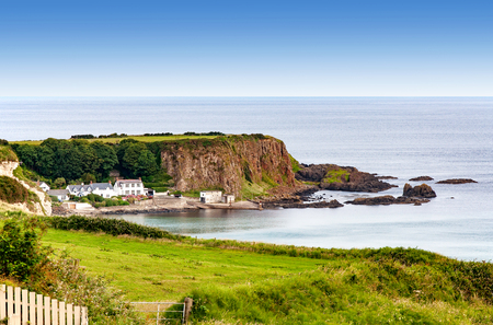 Atlantic coast with a steep rocky cliff and houses in County Antrim, Northern Ireland, UKの写真素材