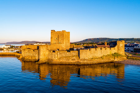 Medieval Norman Castle in Carrickfergus near Belfast in sunrise light. Aerial view with water reflectionのeditorial素材