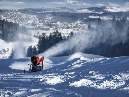 Snow making machine, called also snow cannon or snow gun in action. Bialka Tatrzanska ski resort in Poland in the backgroundの写真素材