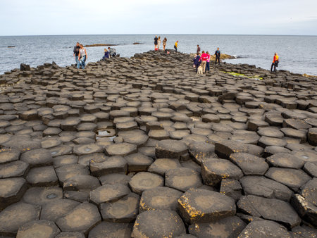 County Antrim, Northern Ireland, UK â July 17, 2019: Visitors on Giantâs Causeway, unique hexagonal geological formation of volcanic basalt rocks. Famous tourist attraction of Northern Irelandのeditorial素材