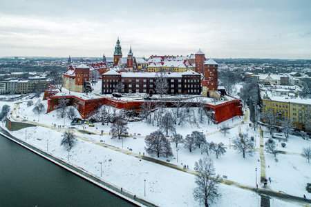 Historic royal Wawel Castle and Cathedral in Cracow, Poland, with Vistula River, walking people, snow and promenade in winterのeditorial素材