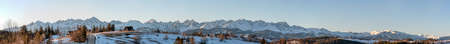 Extra wide full winter panorama of Tatra mountains in sunrise light, with a road houses and forests in Podhale region in Polandの写真素材
